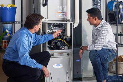 HVAC technician explaining furnace repair and maintenance to a homeowner in Maricopa, AZ